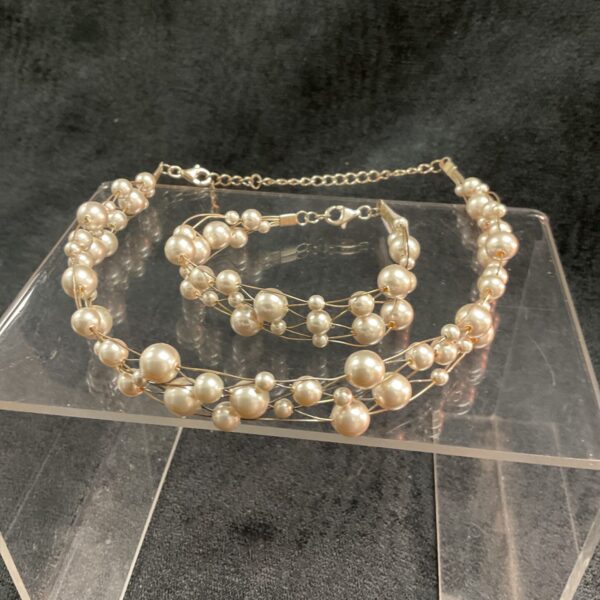 Silver tone faux pearl necklace and bracelet set on display.