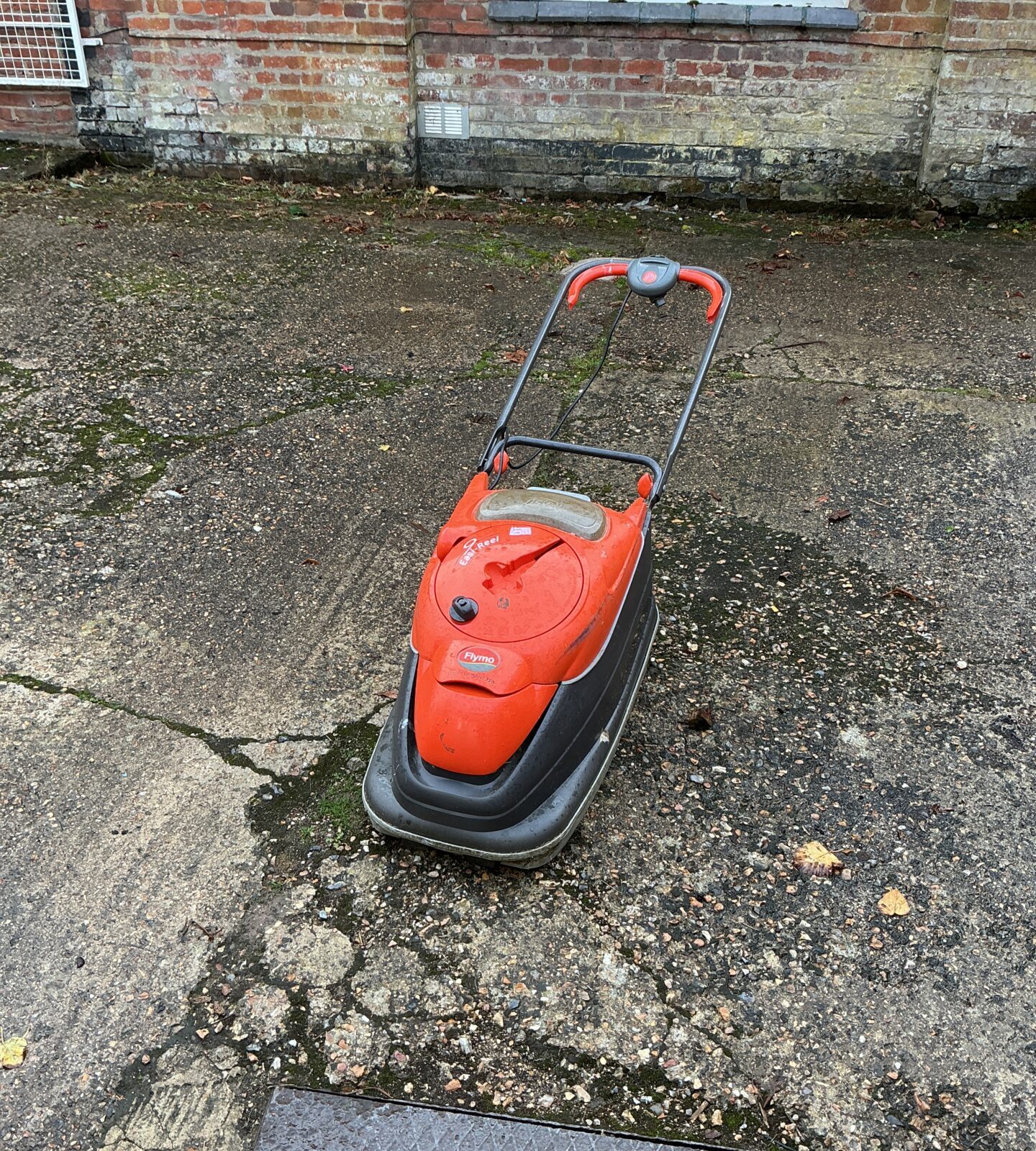 Vintage Flymo electric lawnmower in a garden setting.