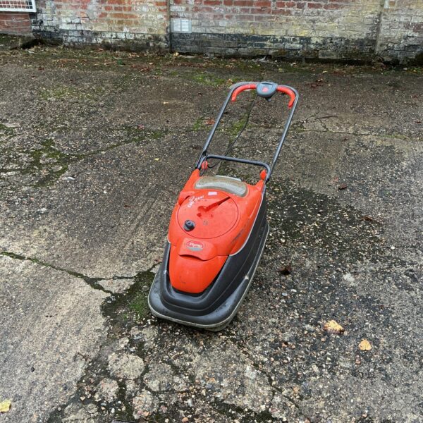 Vintage Flymo electric lawnmower in a garden setting.