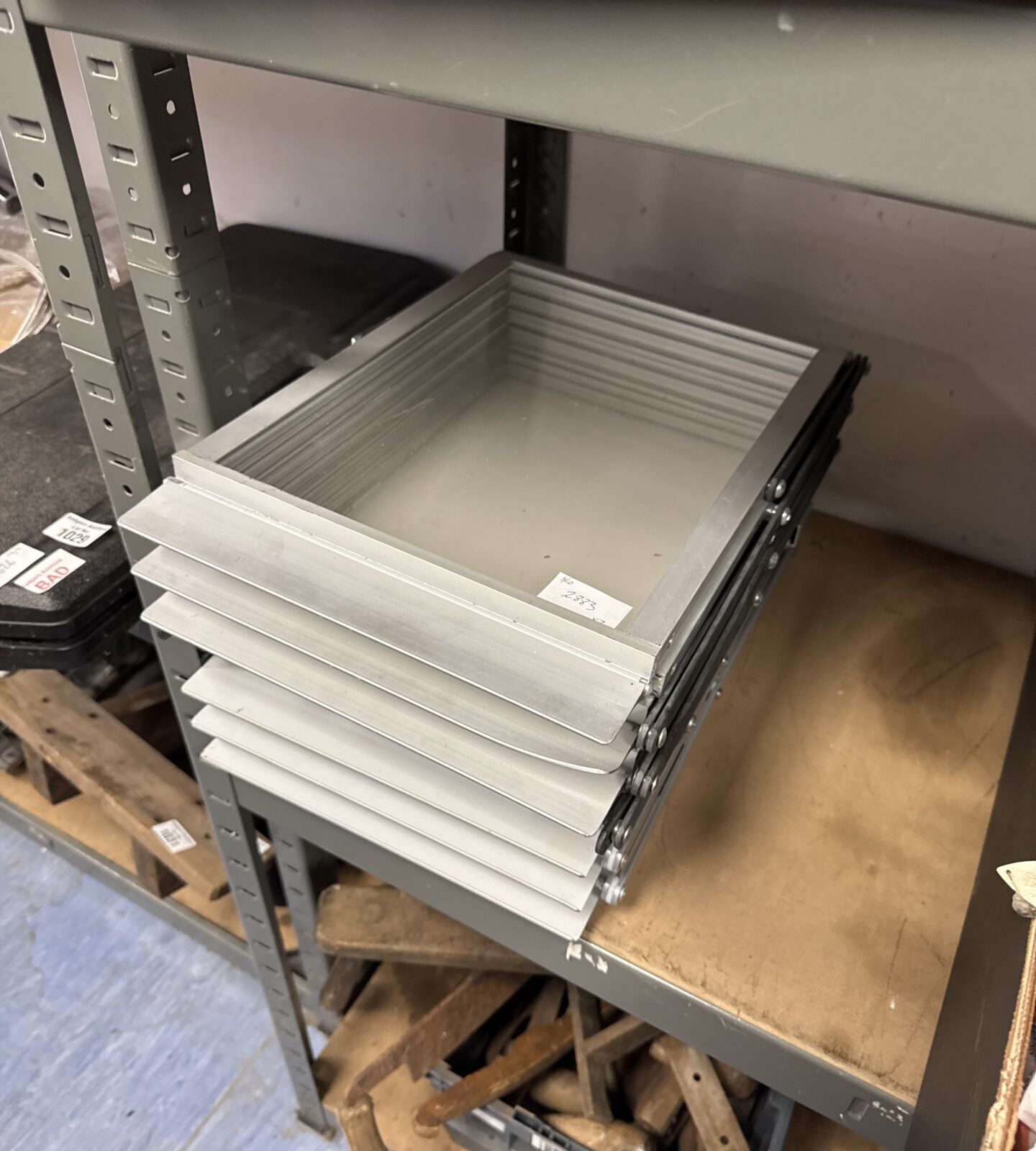 Silver folding A4 leaflet stand on a metal shelf.