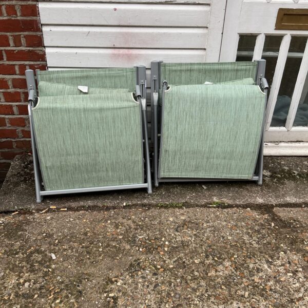 Two green striped folding sun lounges in a garden setting.