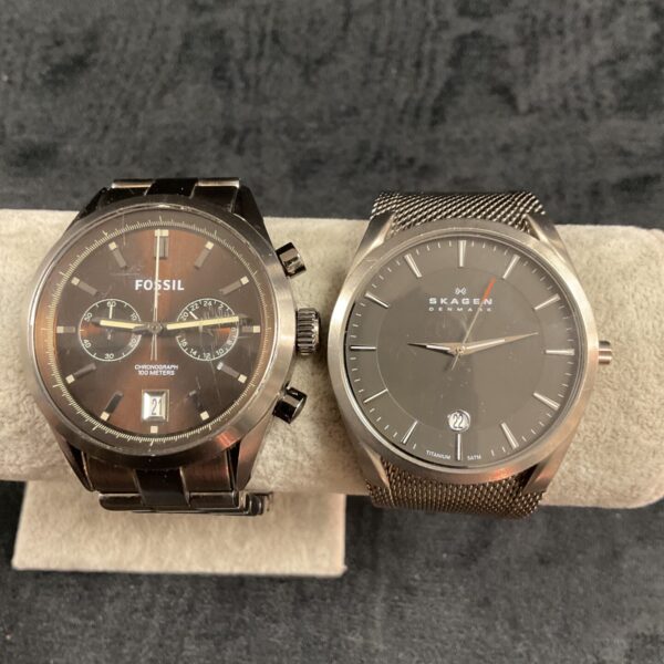 Pair of Fossil and Skagen quartz wristwatches on display.