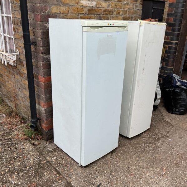White Frigidaire tall freezer standing outside a building.
