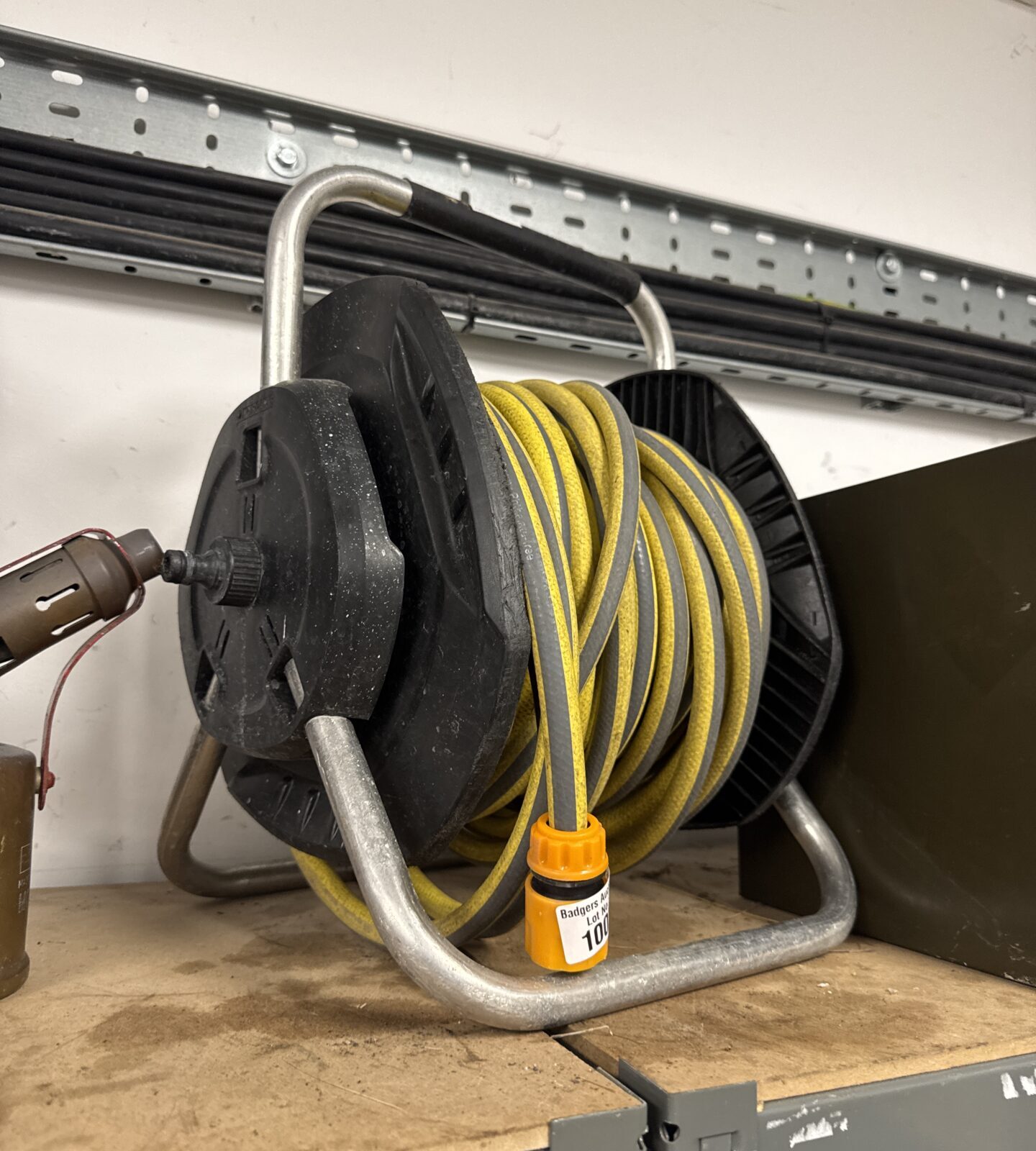 Close-up of a used garden hose reel with a yellow hose.