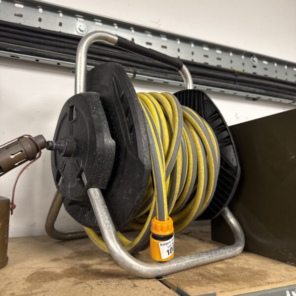 Close-up of a used garden hose reel with a yellow hose.
