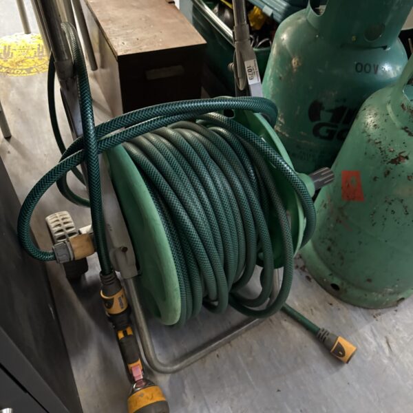 Green garden hose reel with yellow sprinkler attachment.