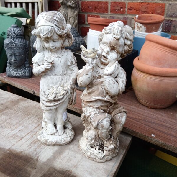 Vintage plastic garden ornaments of a boy and girl in a garden.