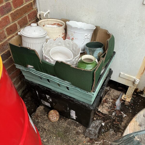 Collection of vintage garden planters and pots in a green crate.