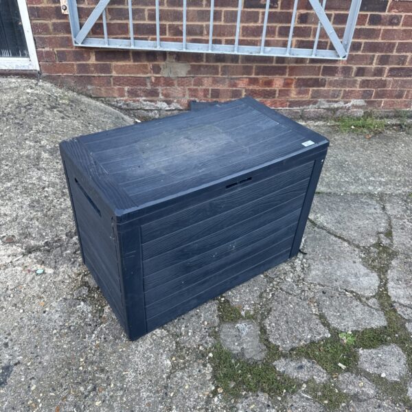 Black plastic garden storage bin in a garden setting.
