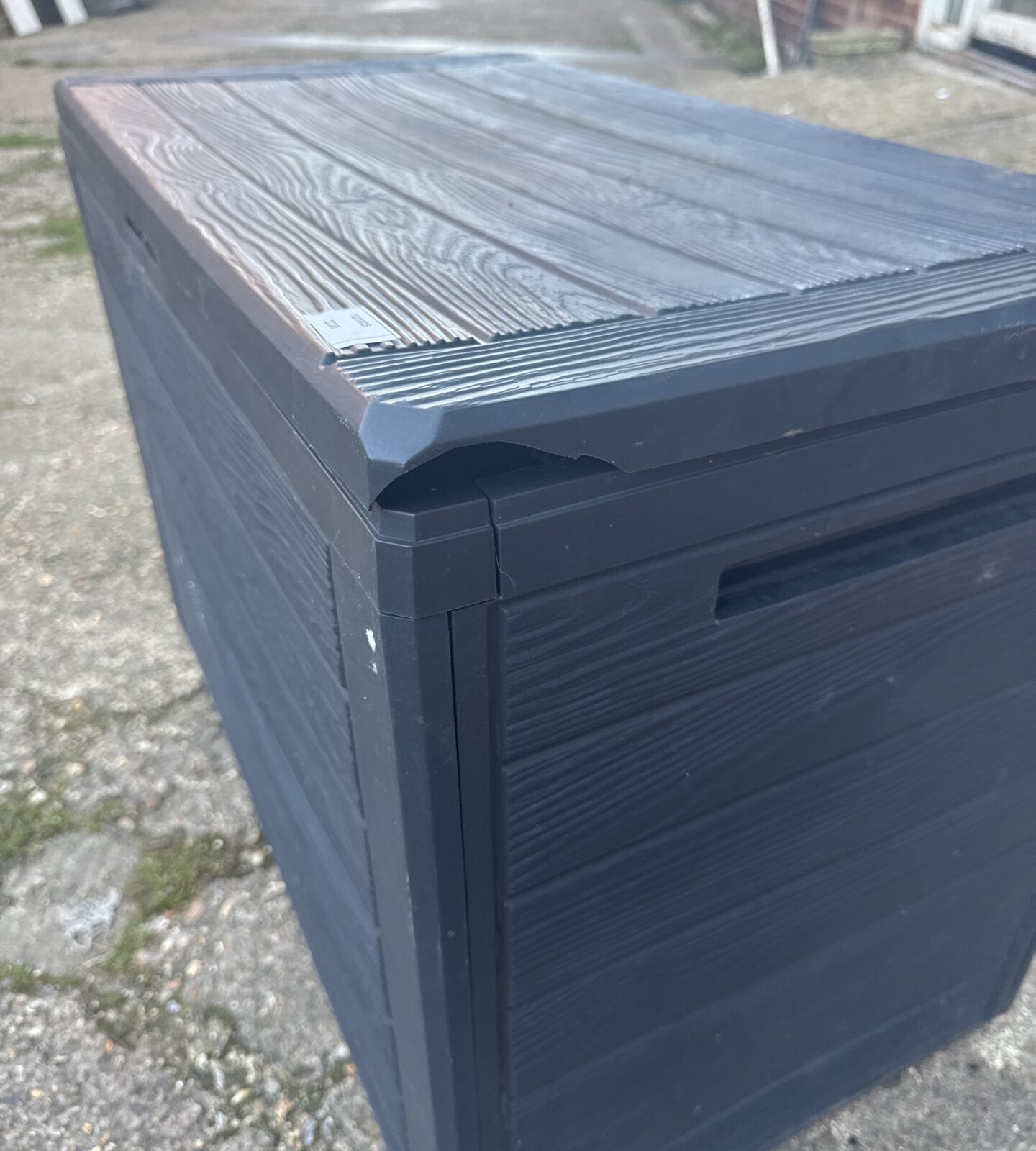 Top view of a black plastic garden storage bin with wood-effect texture.