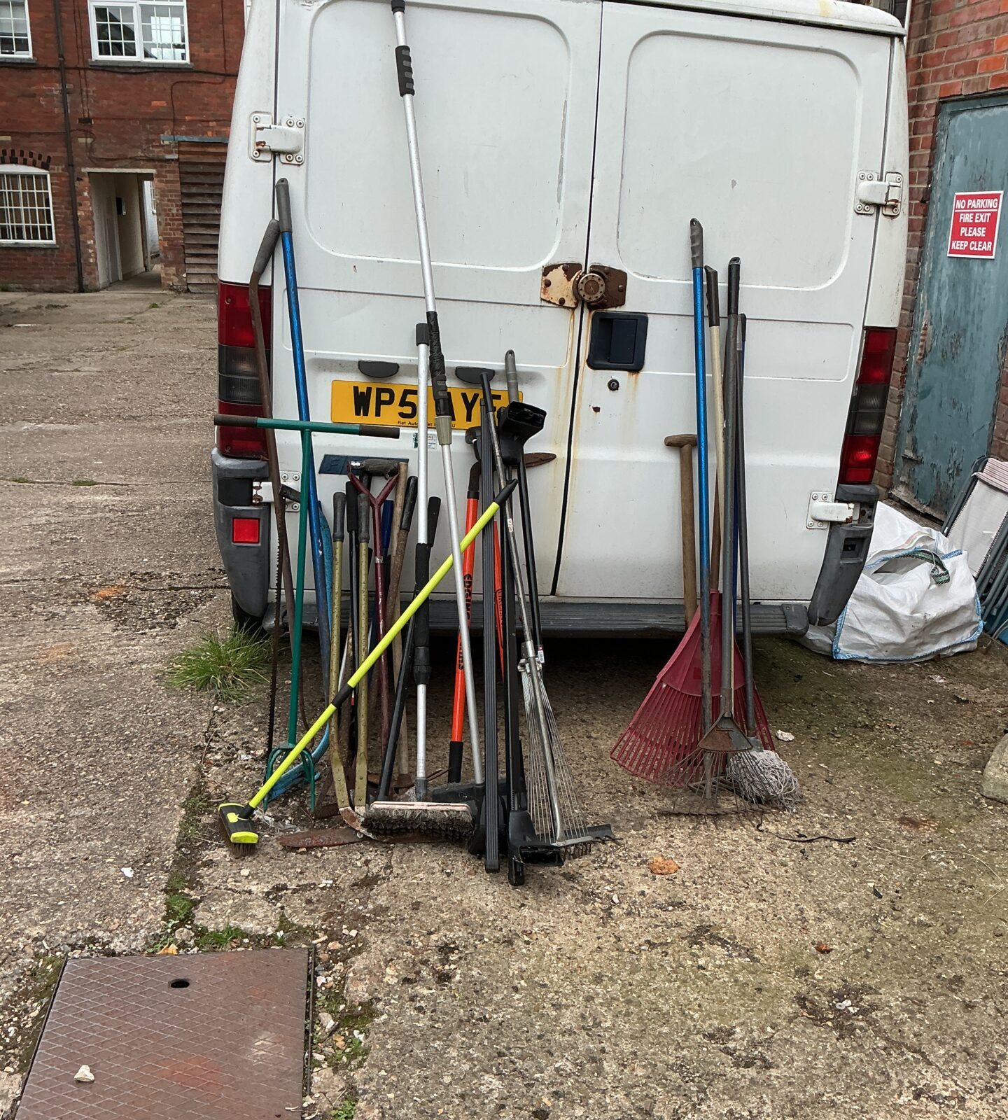 Assorted garden tools leaning against a van, job lot.
