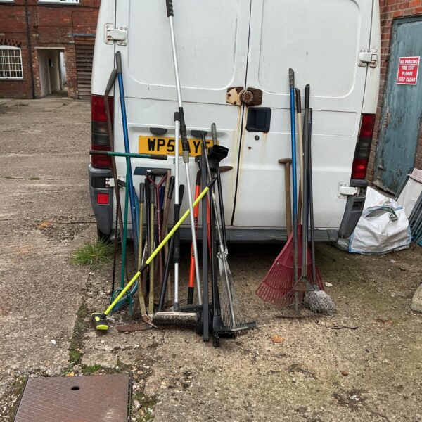 Assorted garden tools leaning against a van, job lot.