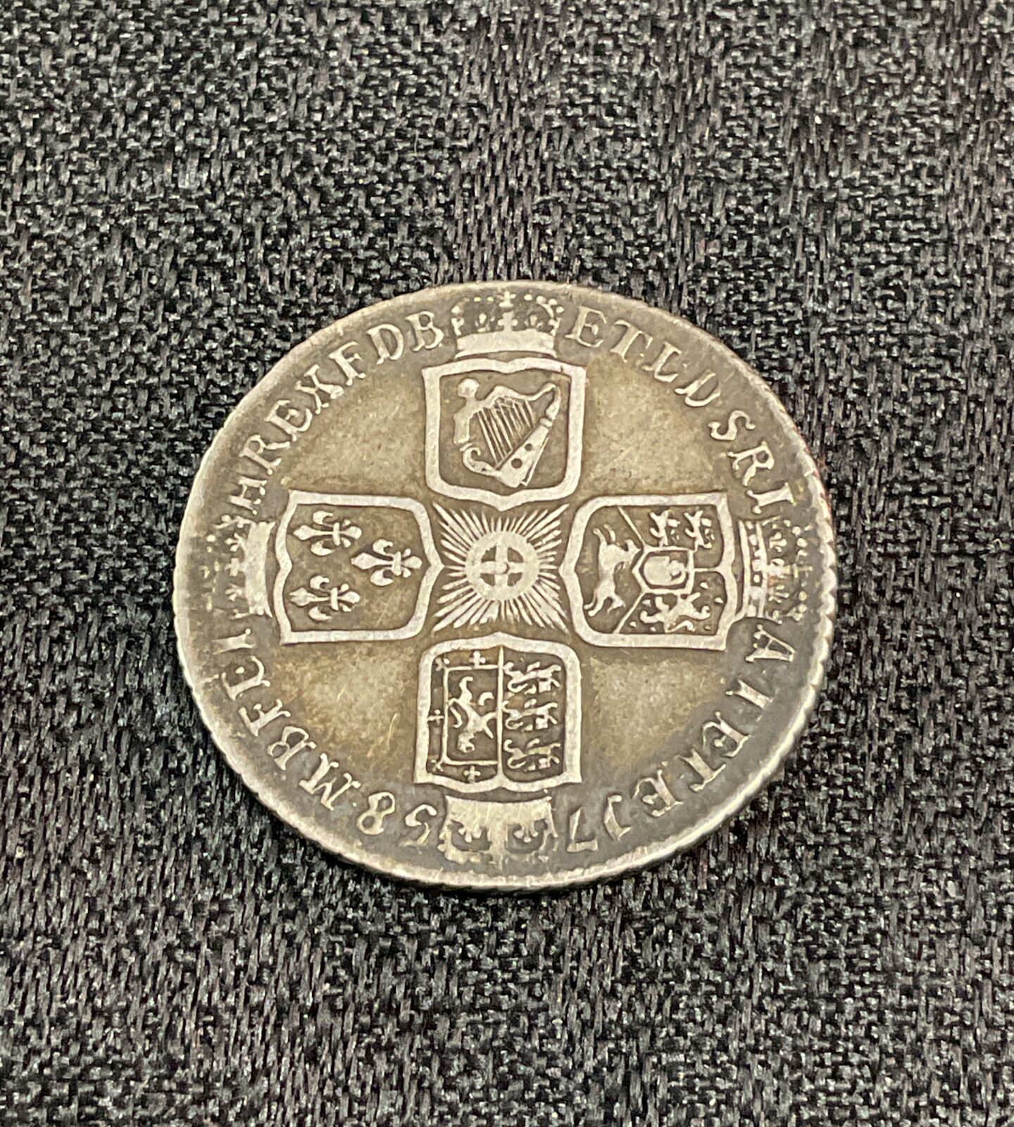 Antique George II shilling coin from 1758, showing the king's portrait.