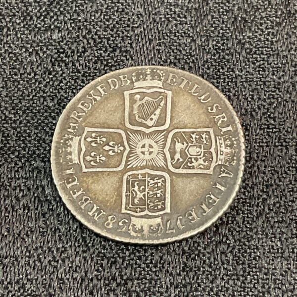 Antique George II shilling coin from 1758, showing the king's portrait.
