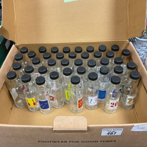 Numbered glass advent bottles in a cardboard box.