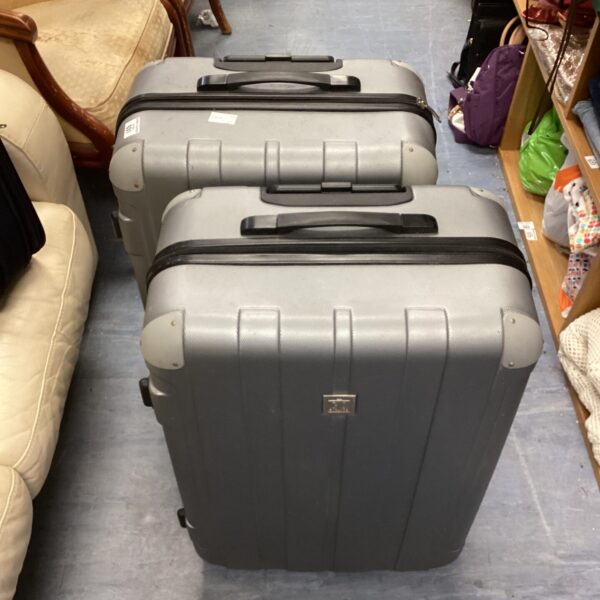 Pair of grey Go Explore suitcases with wheels and extending handles.