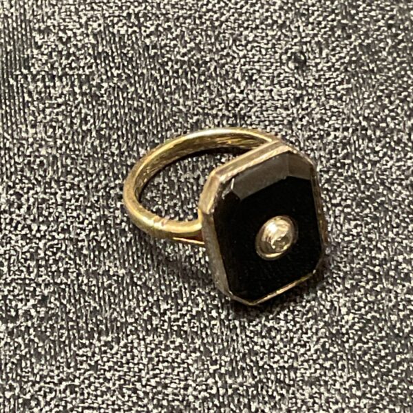 Gold ring with black stone, close-up view.