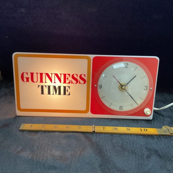 Vintage Guinness bar clock lamp with red housing and white face.