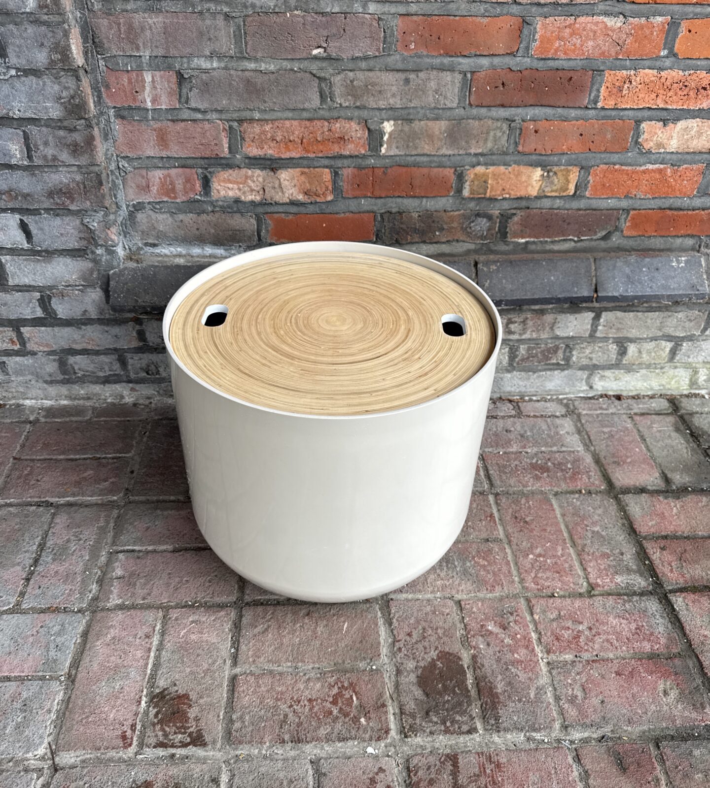 White Habitat drum side table against brick wall.