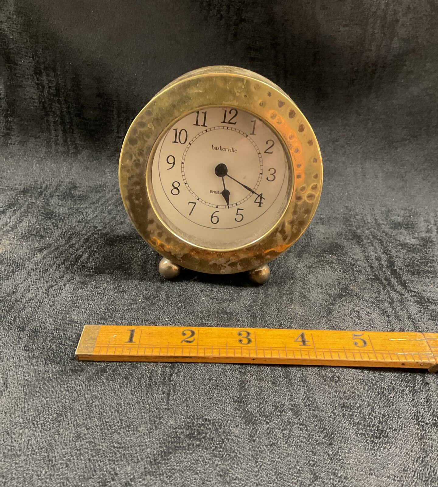 Vintage hammered brass mantle clock with clear dial.