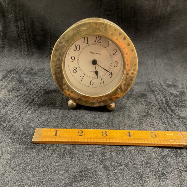 Vintage hammered brass mantle clock with clear dial.