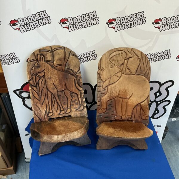 Pair of vintage hand-carved child’s seats with face details.