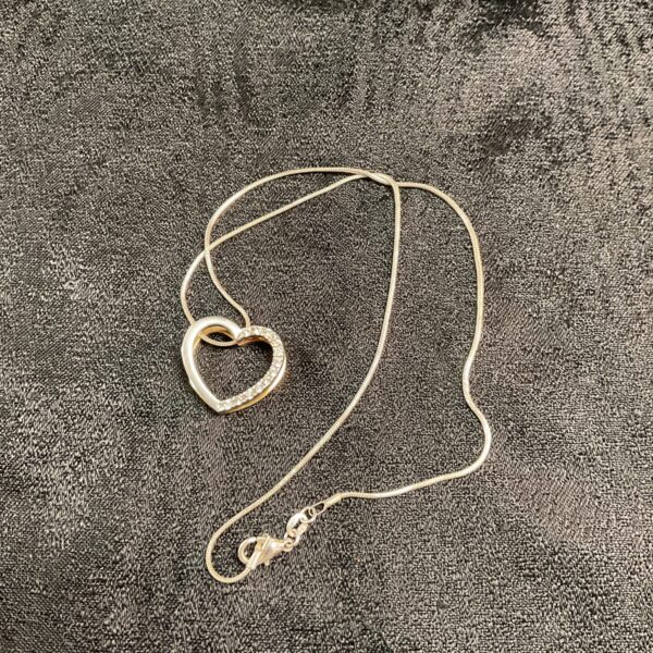 Silver heart pendant necklace on a delicate chain.