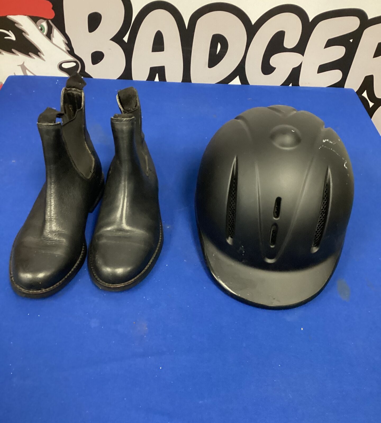 Black horse riding boots and helmet set for equestrian sports.