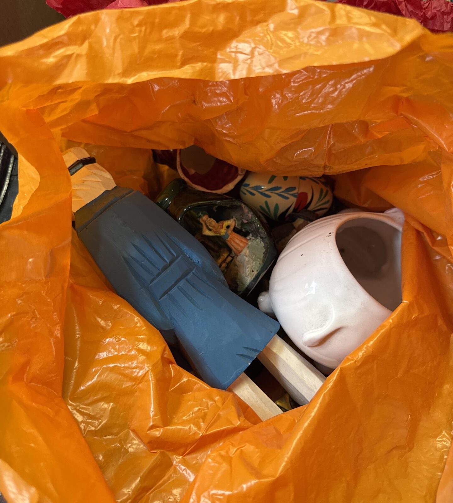 Orange bag filled with house clearance lot items.