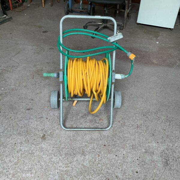 Metal Hozlock hose reel with green garden hose wound around it.