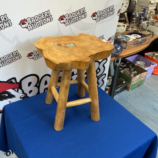 Rustic teak stool with natural wood grain and three legs.