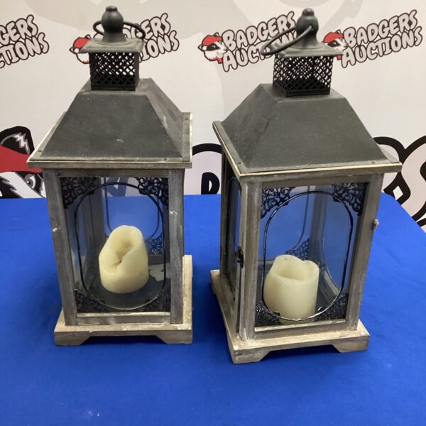 Two rustic wooden candle lanterns with pillar candles inside.