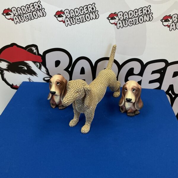 Three vintage porcelain dog figurines on a dark surface.