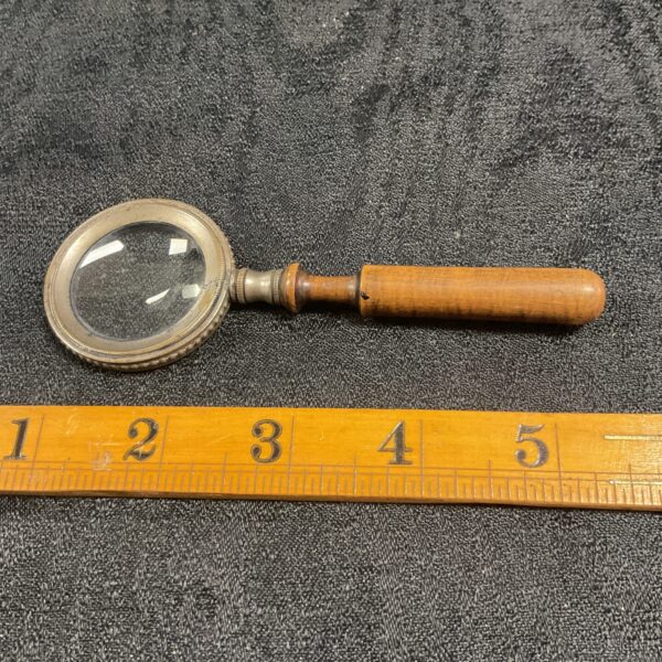 Antique magnifying glass with brass and wood handle, vintage reading tool.