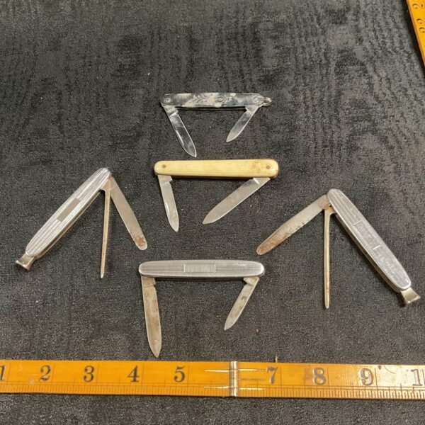 Vintage lot of pocket knives and pipe tools on a ruler.