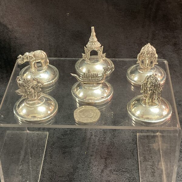 Set of six Thai sterling silver place card holders on display.