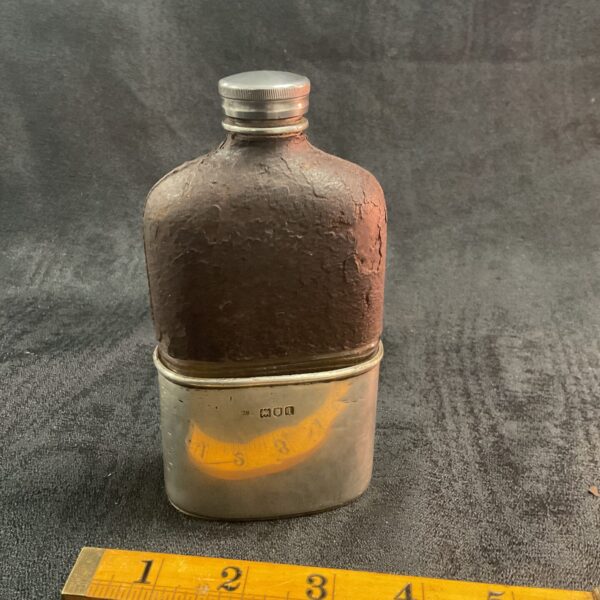 Antique silver hip flask with leather casing, showing wear.