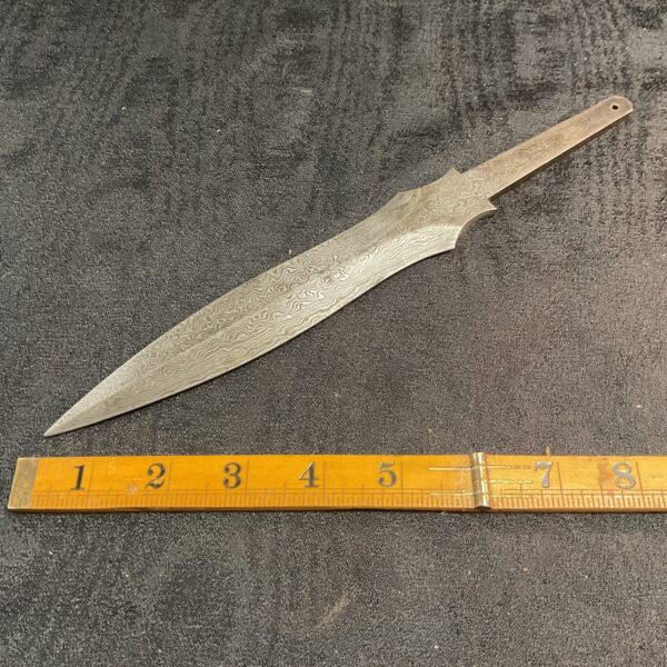 Unfinished Damascus steel knife blade with swirling pattern.
