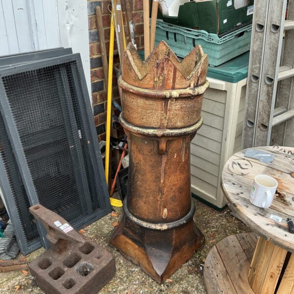 Large weathered Victorian terracotta chimney pot in a garden setting.
