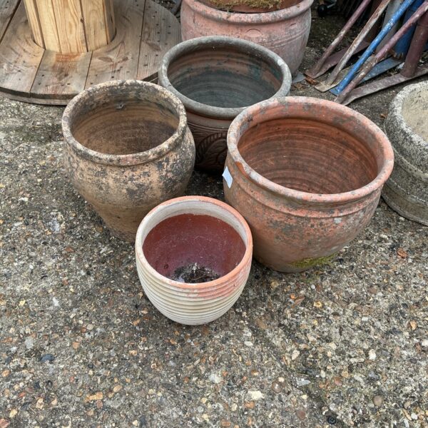 Four vintage terracotta garden planters in a garden setting.