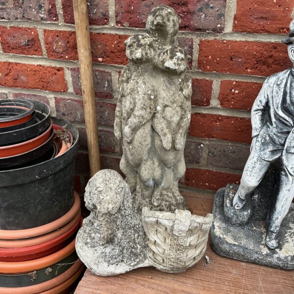 Close-up of vintage concrete garden dog figurines in a garden.