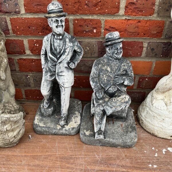 Vintage Laurel and Hardy garden figurines in a garden setting.