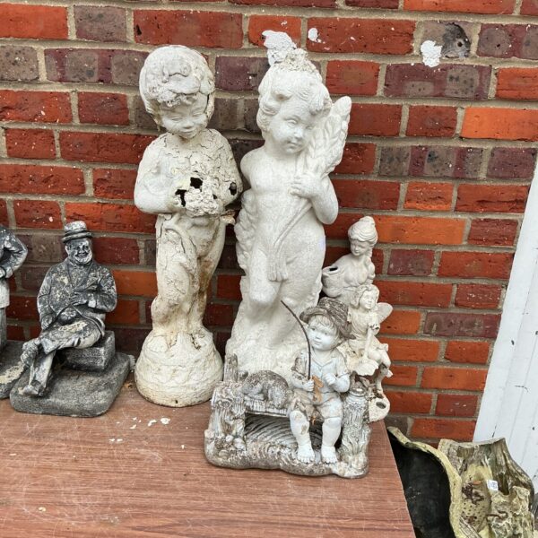 Vintage cherub statue amongst a quantity of garden ornaments.