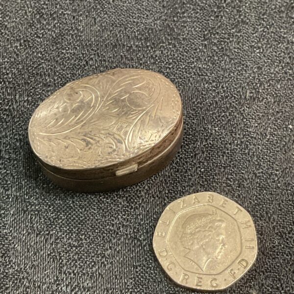 Antique silver pill box with floral embossed lid.