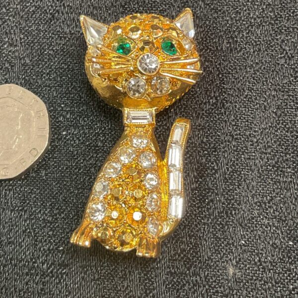 Vintage gilt cat brooch with green eyes and white stones.