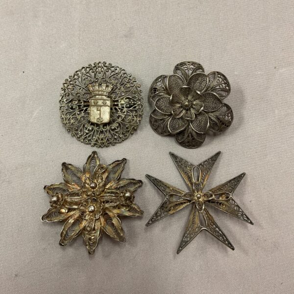 Vintage filigree silver brooches with delicate floral designs.