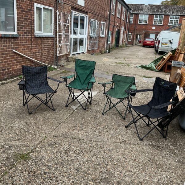 Four folding camping chairs in a courtyard setting.