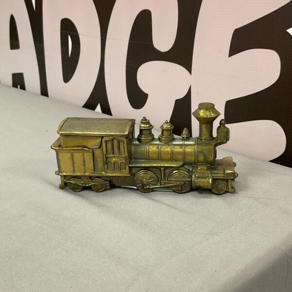 Vintage brass steam train lighter on a white surface.