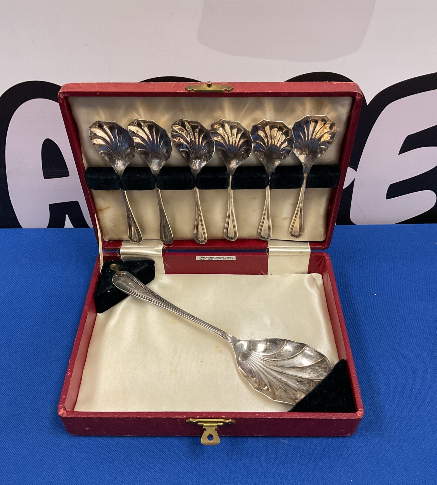 Vintage James Walker silver plate dessert spoon set displayed on a surface.