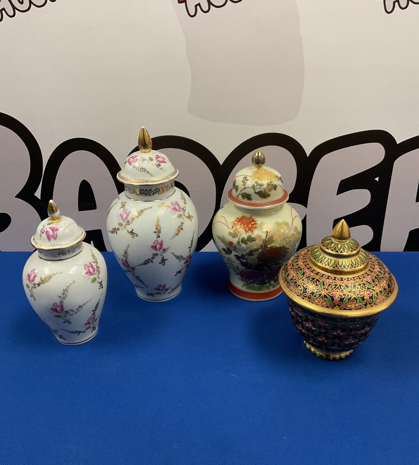 Four antique Japanese ginger jars on a blue surface.